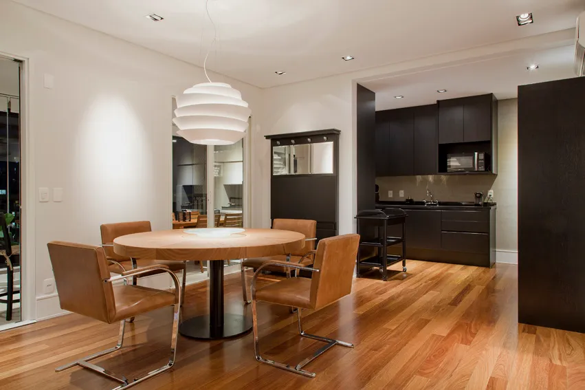Sala de jantar com mesa redonda de madeira e cadeiras de couro