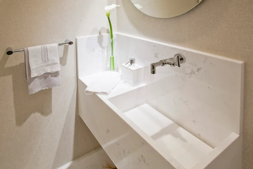 Lavabo com cuba esculpida em mármore branco e torneira de parede