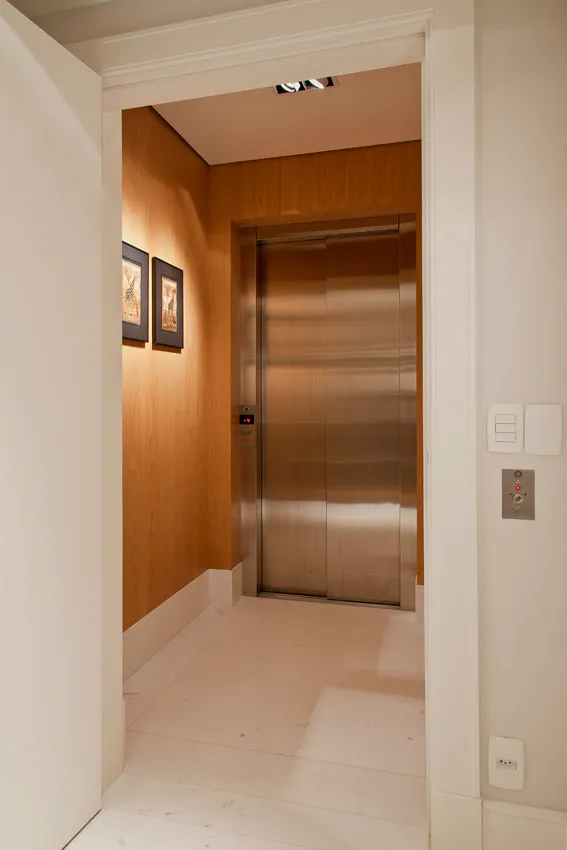 Hall do elevador privativo com painéis de madeira clara
