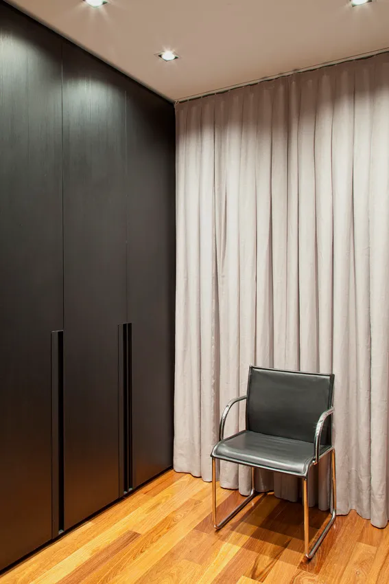 Closet com armários escuros sob medida e cortina de linho