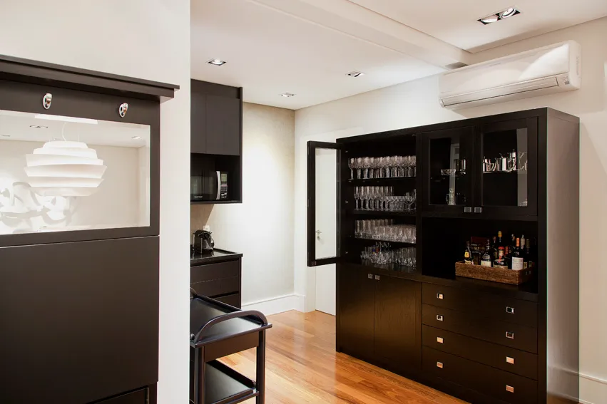 Cristaleira preta com taças e bar em apartamento