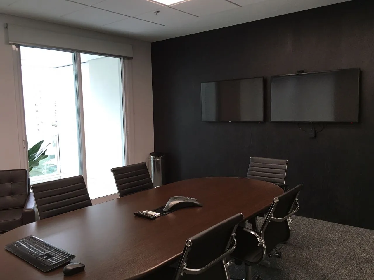 Sala de reunião com parede escura e duas telas