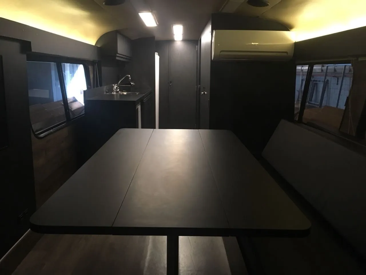 Interior do motorhome com mesa e cozinha em preto